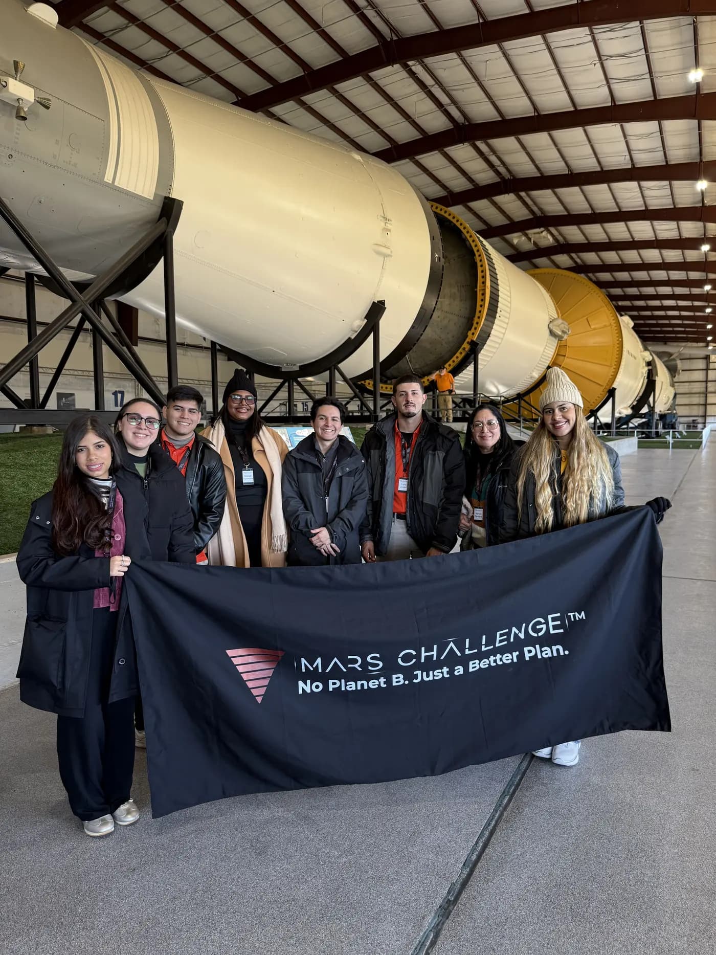 Delegación de Mars Challenge frente al cohete Saturno V
